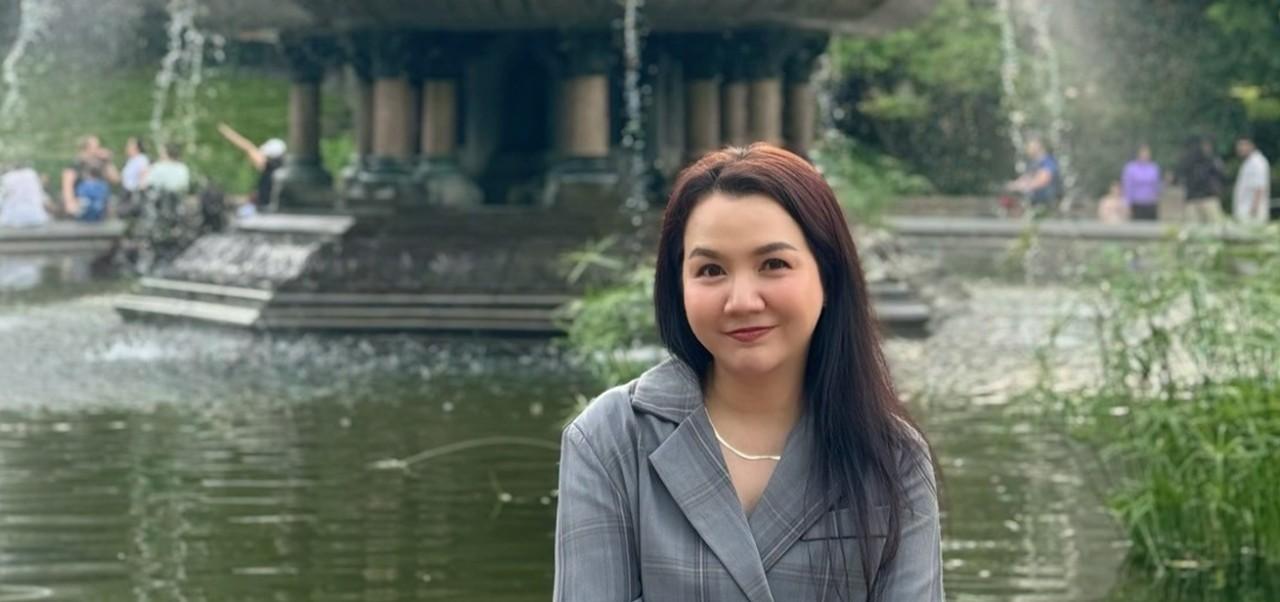 Siriluck Mim Rattanawaropas, NYU SPS Division of Programs in Business alumnus, smiles for the camera while sitting at a large fountain.