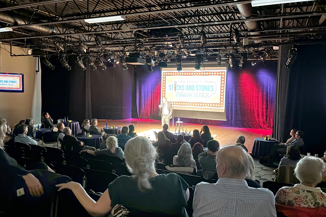 A performer does a comedy routine on stage at Abby Russell's Sticks and Stones Comedy Club