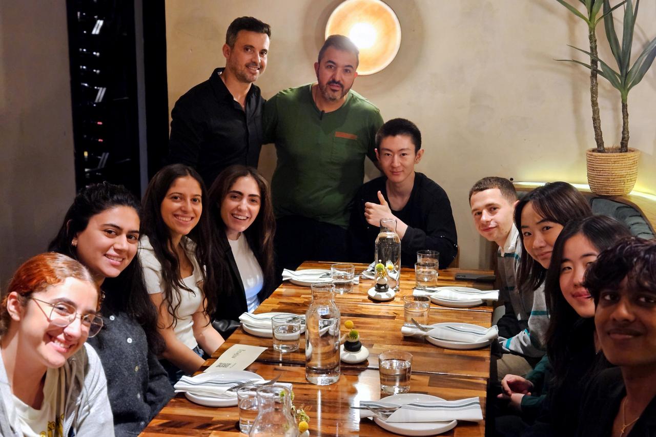 NYU SPS Continuing Education instructor Ronald Naples smiles at a table full of students at Berimbau Kitchen with the restaurant owner, a former NYU CE student