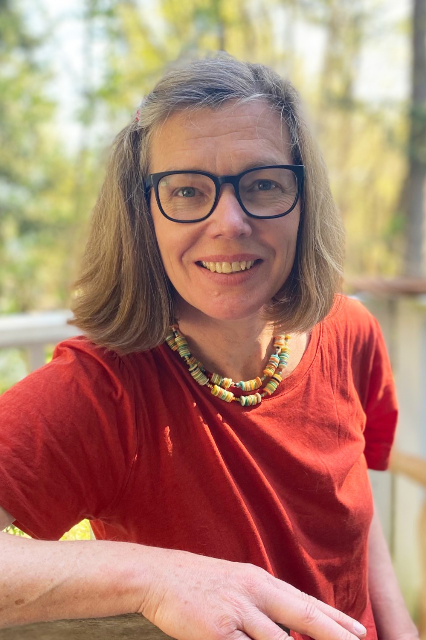 Headshot of Barbara Karsch who wears a red t-shirt with a neutral outdoor background