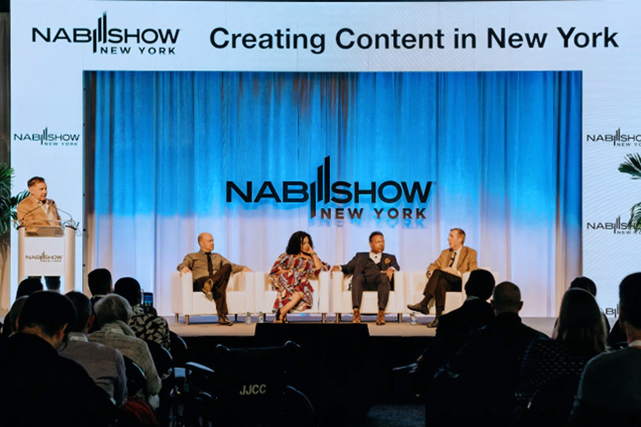 Panel of four speakers seated on stage at NAB Show New York, discussing content creation. Audience listens attentively.