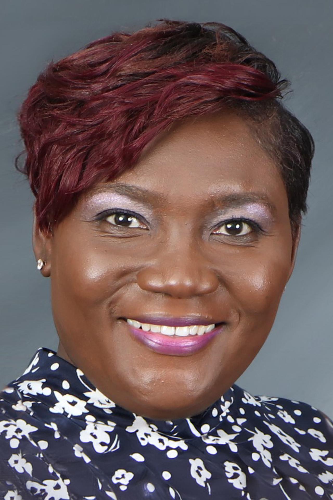Donna Kelly poses for a close-up headshot in front of a grey background