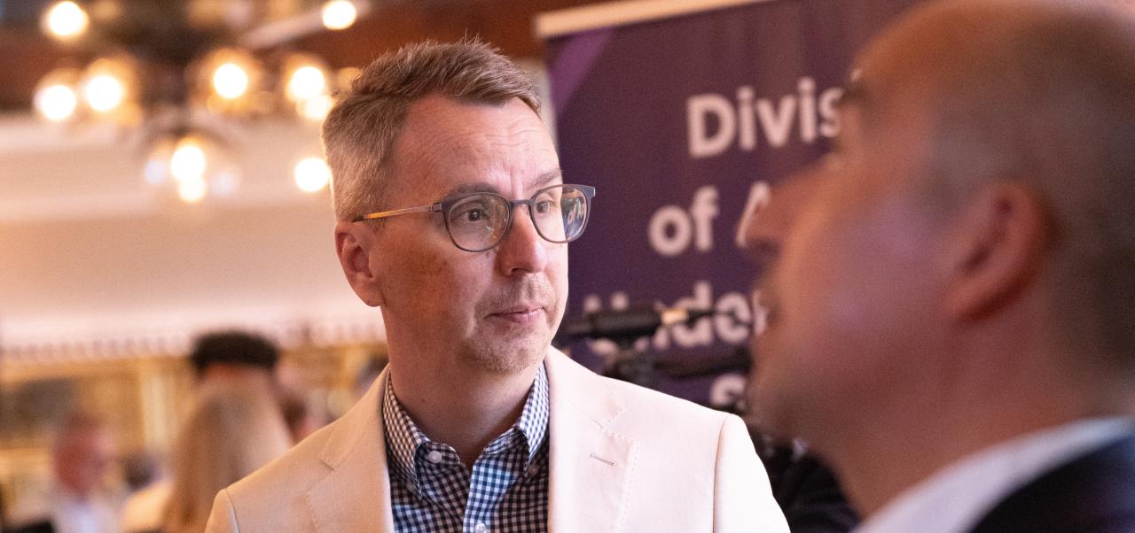 Douglas Harrison, Associate Dean, Division of Applied Undergraduate Studies at NYU SPS, engages with a colleague at a formal event.
