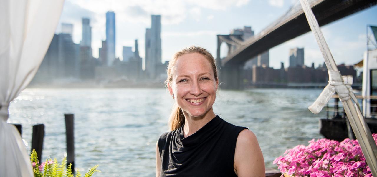 With the Brooklyn bridge and the East River in the background, Michaela Boruta wears a black blouse while smiling for a photo