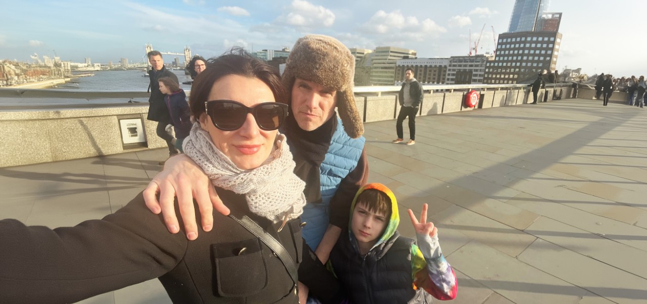 Dr. Steven Goss,  Clinical faculty member and chair of the Management and Technology program in the Division of Programs in Business at NYU SPS, poses for a photo with his wife and son on a bridge in London overlooking Big Ben.