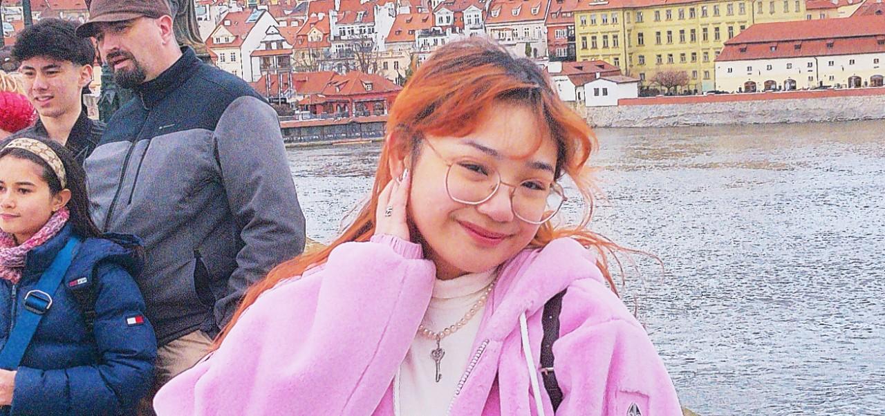 Brianne Oliva, student at the Center for Publishing and Liberal Arts, NYU SPS, poses for a photo at an urban river in Europe.