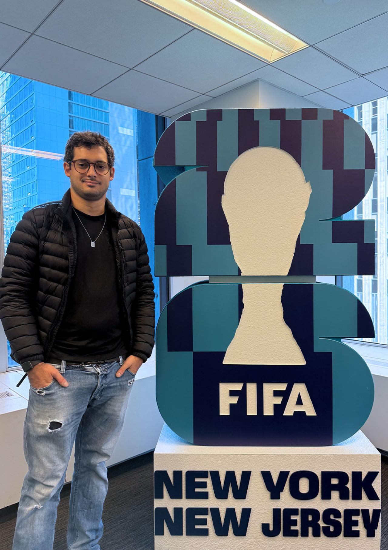 Gustavo Giusti stands beside a FIFA display.