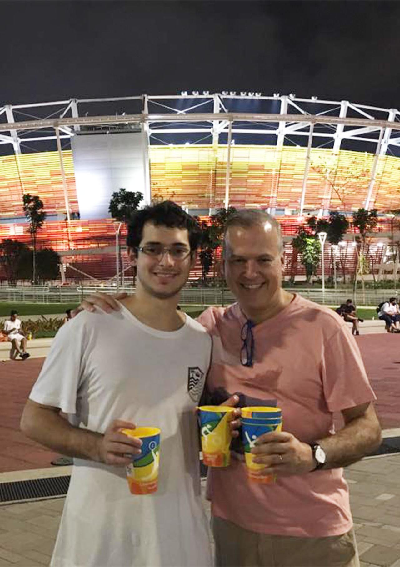 Gustavo Giusti poses for a photo with a friend outside a soccer stadium.