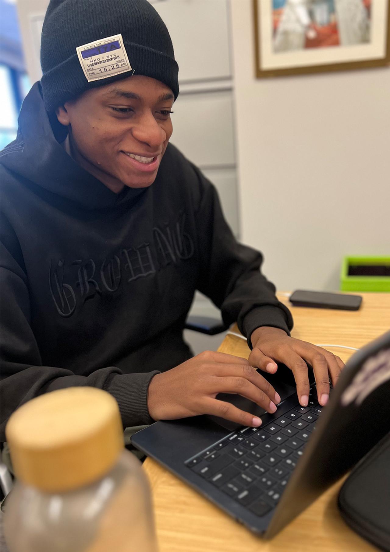 Ronald Medor typing on a laptop while smiling