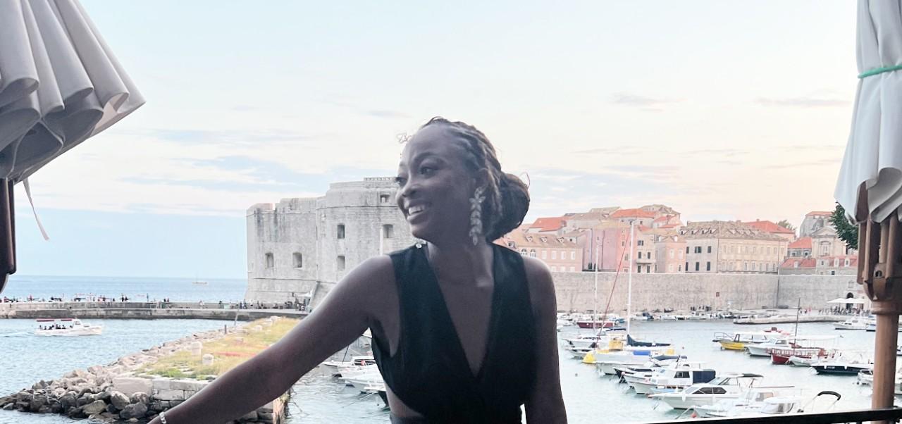Zainab Aregbe, Schack Institute of Real Estate at NYU SPS alumnus, poses for a selfie while exploring  a historic marina full of watercraft.