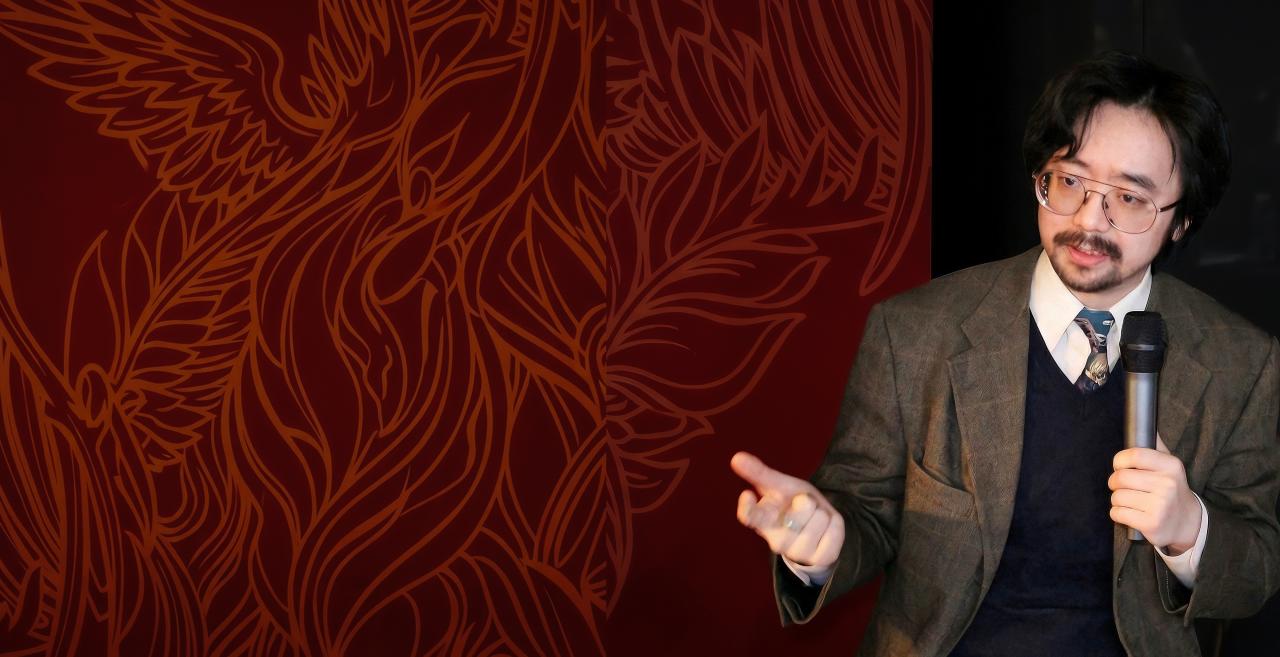 Shaoyu Yuan speaking into a microphone during a presentation