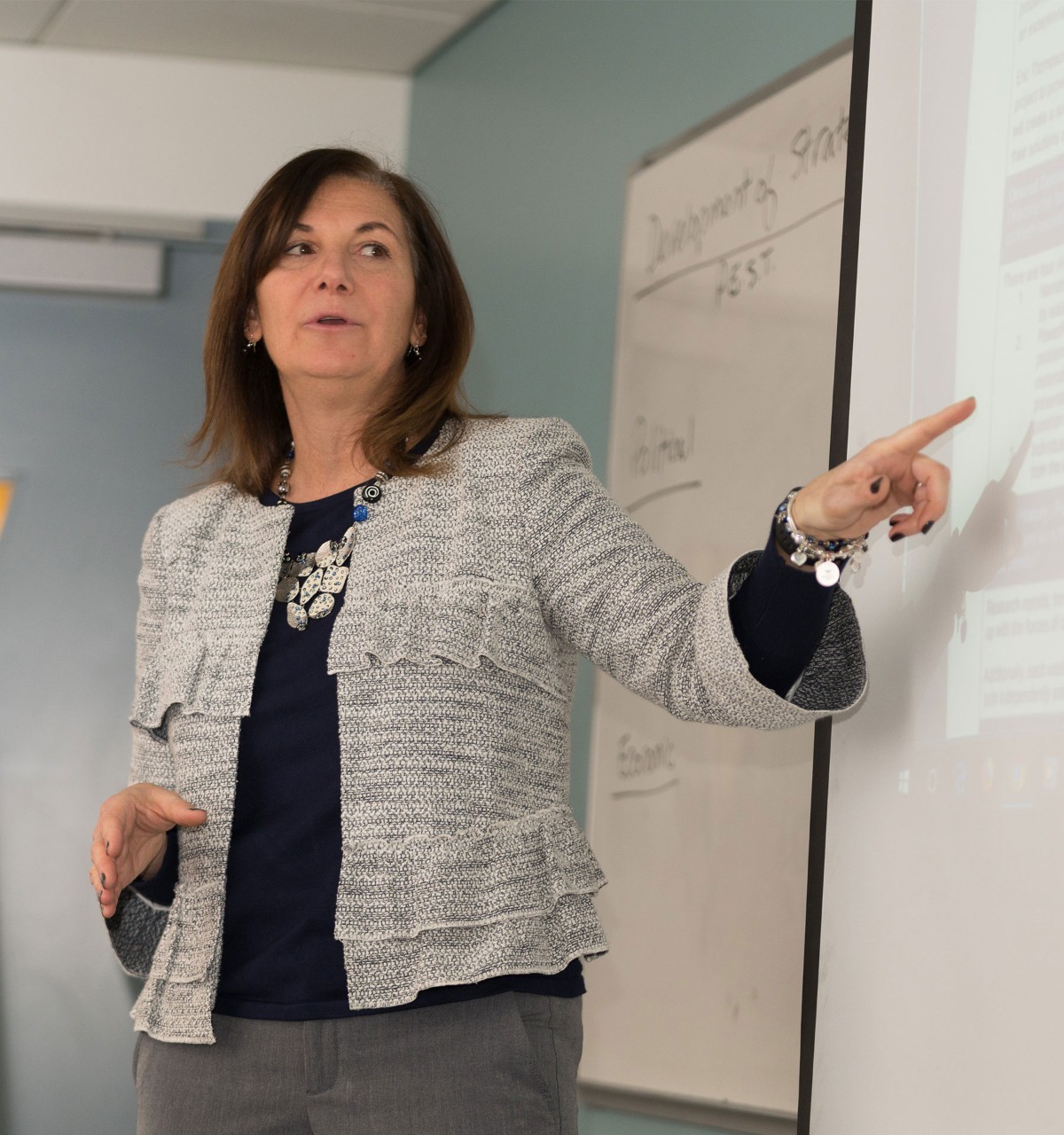 Woman speaking and pointing to projector screen