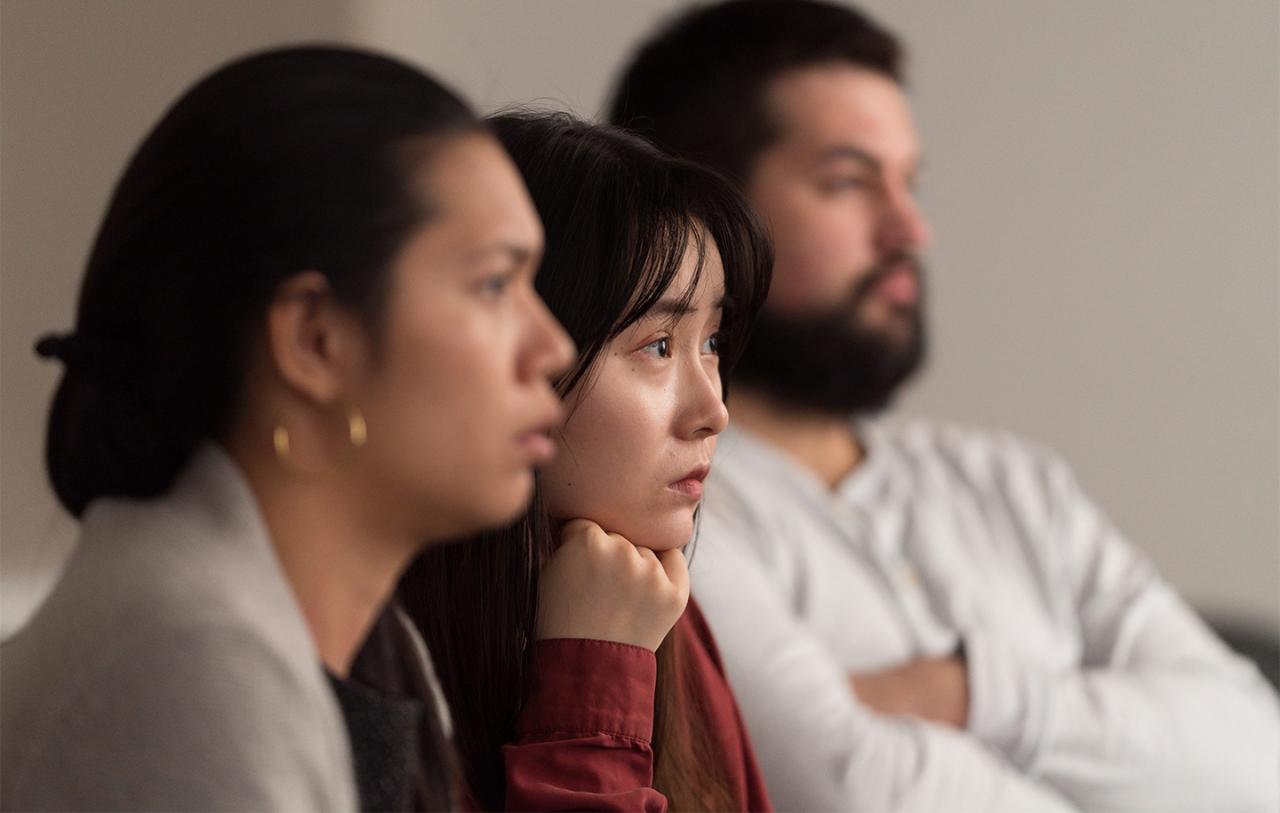 Three people sitting in profile, attentively looking forward.