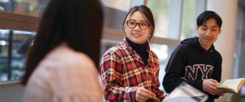 Three NYU SPS students discuss class material in a classroom