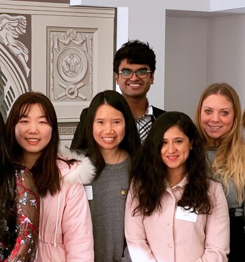 Five NYU SPS Division of Programs in Business scholarship students pose for a photo in an academic building