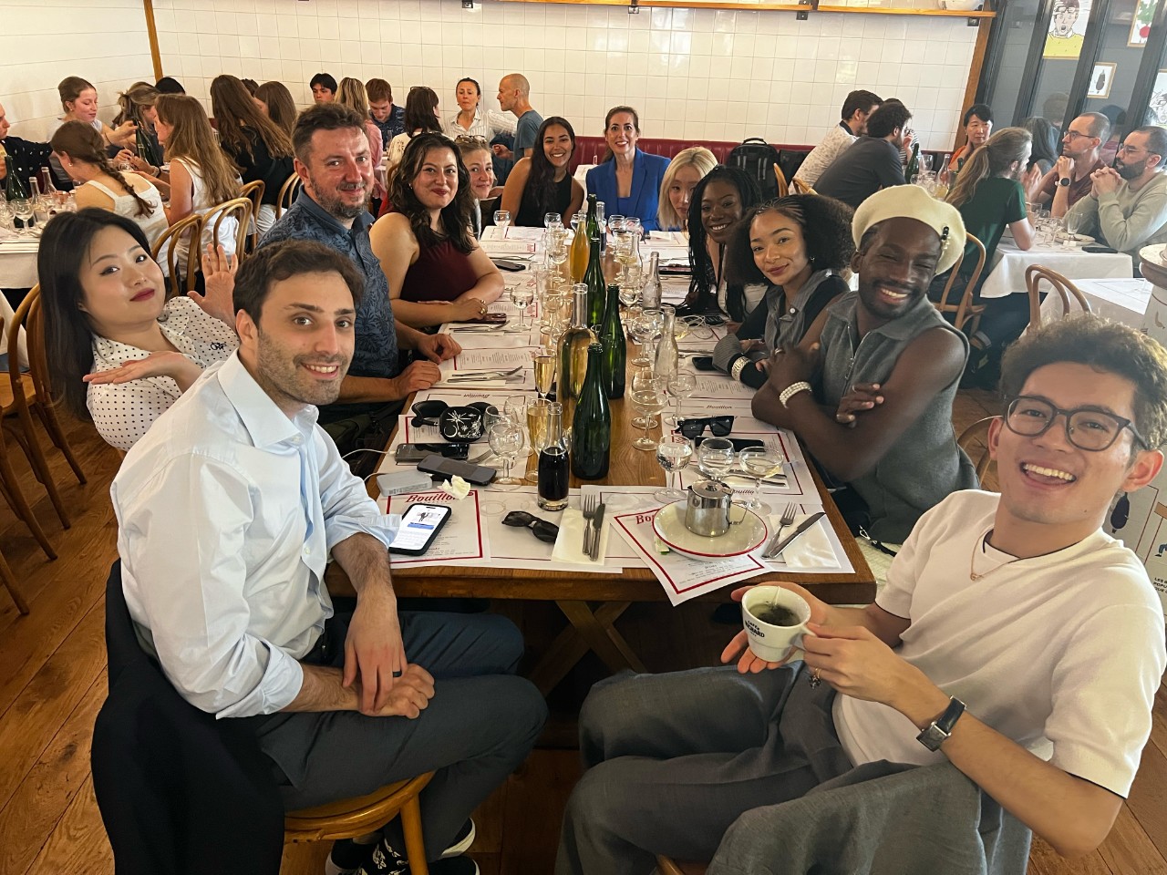 NYU SPS scholarship students smile together at a restaurant table in Paris during the Michael Diamond Cannes Travel Grant trip.