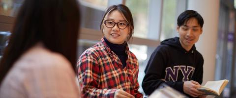 Three NYU SPS students discuss class material in a classroom