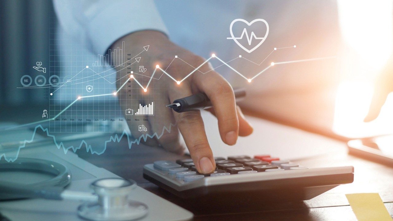 Professional with stethoscope and hand on adding machine.