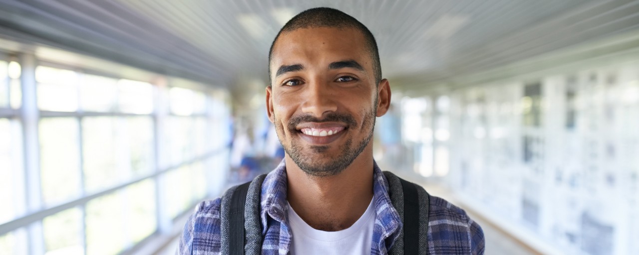Student smiling in college hallway.