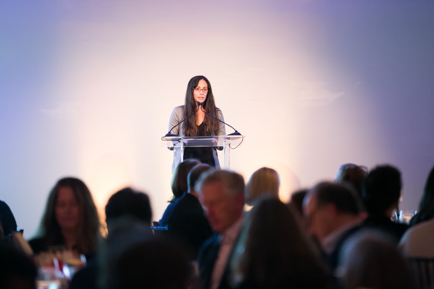 Dr. Kristine Rodriguez Kerr, standing at a podium, speaking at the 2019 Words Without Borders Gala
