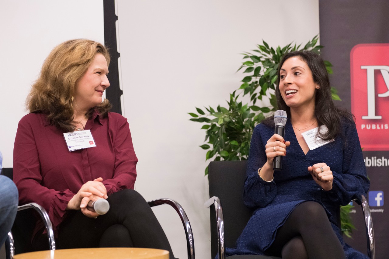 2 women sitting, both with microphones in their hands