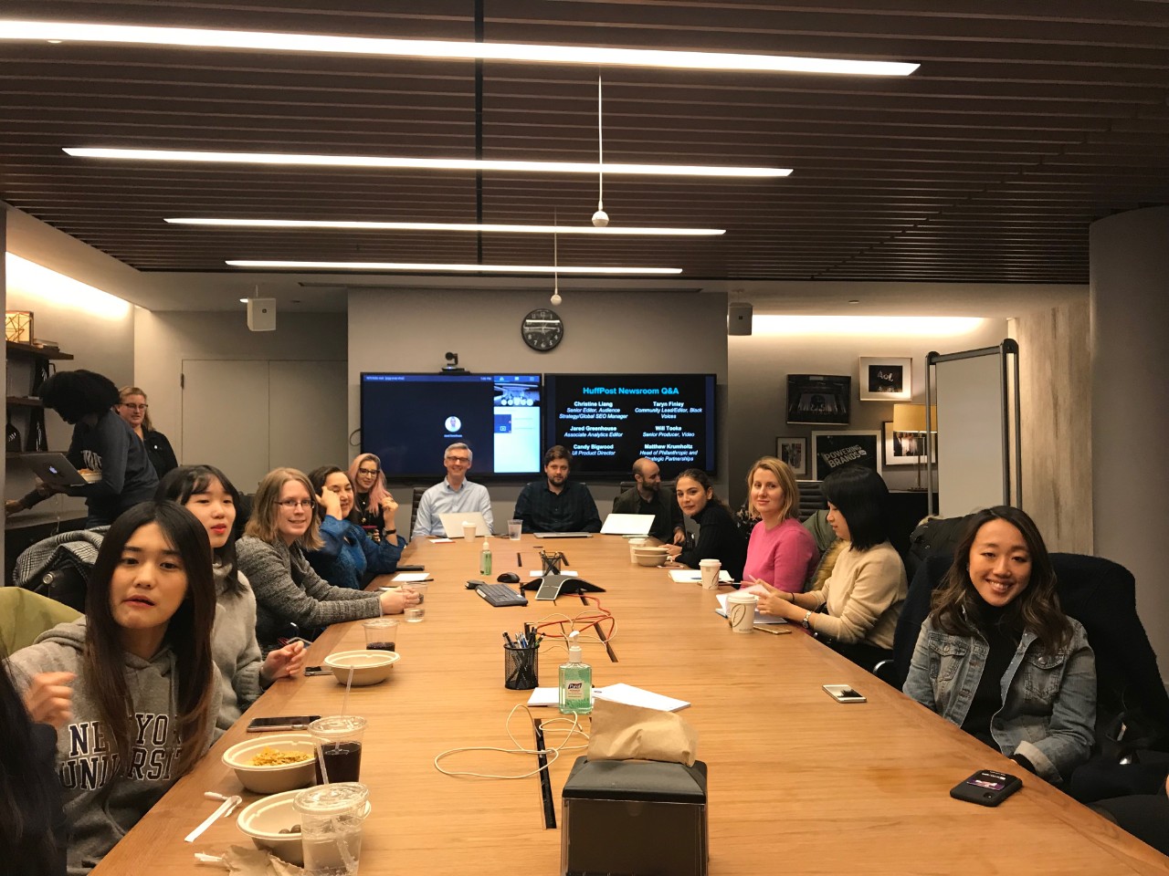 Students sitting around the HuffPost conference desk about to eat lunch