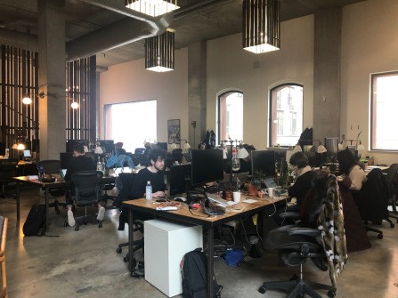 Students sitting at various desks with computers and other accessories at a library