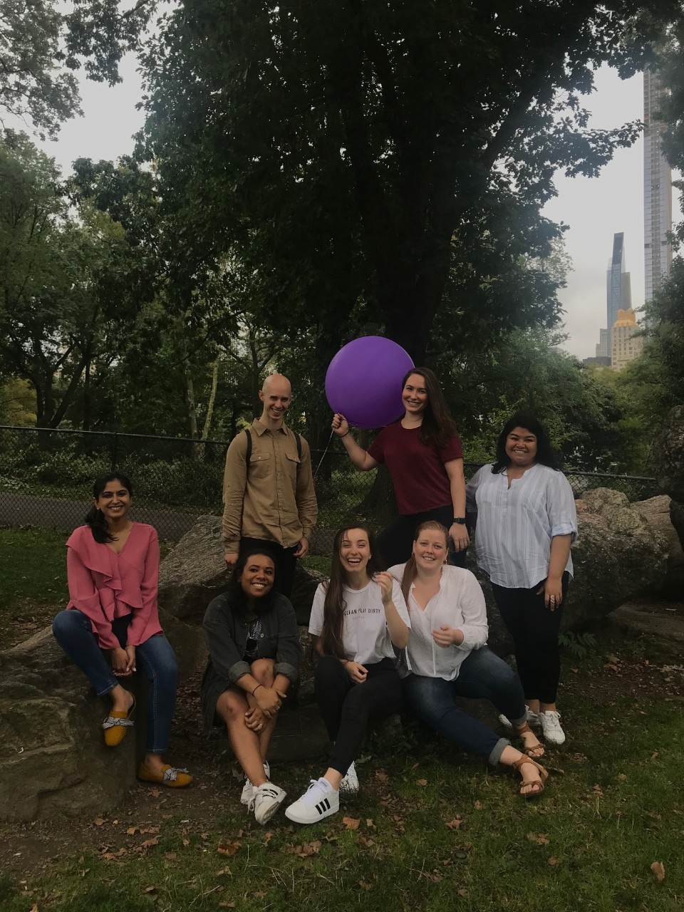 Publishing Students Association (PSA) members pose with a purple balloon on a large rock in NYC's Central Park
