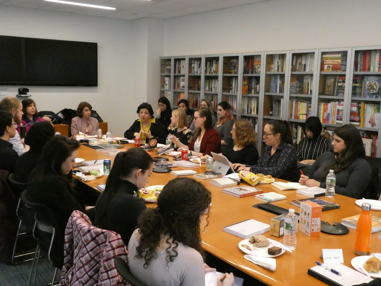 Students sitting at a Crown Publishing conference desk eating, listening, speaking and taking notes