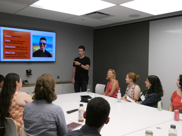 Student presenting on a video screen, in front of others at a conference table