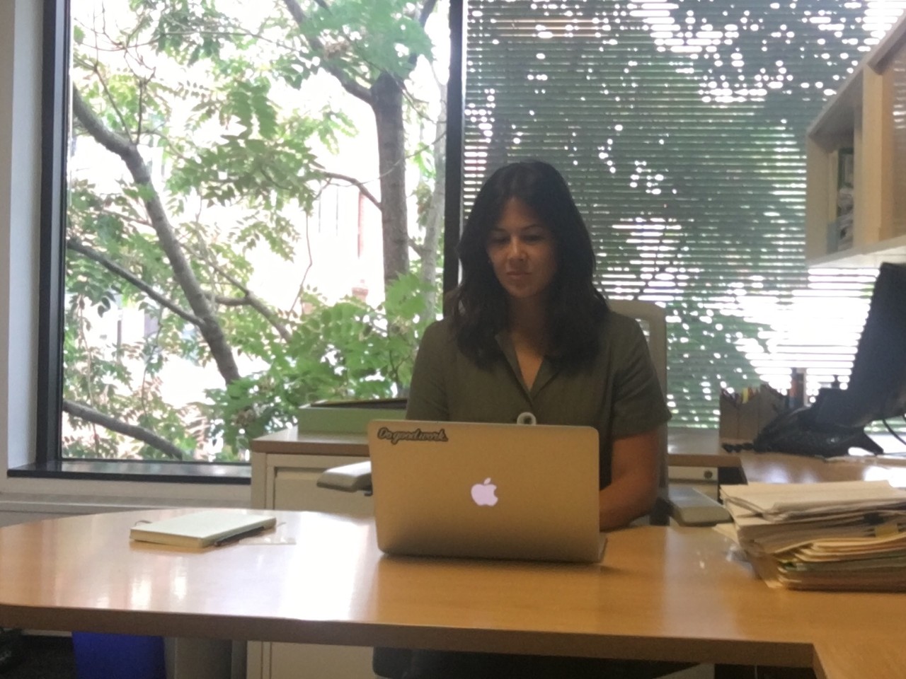 Kim Castro sitting at her desk, working on her Apple MacBook laptop.
