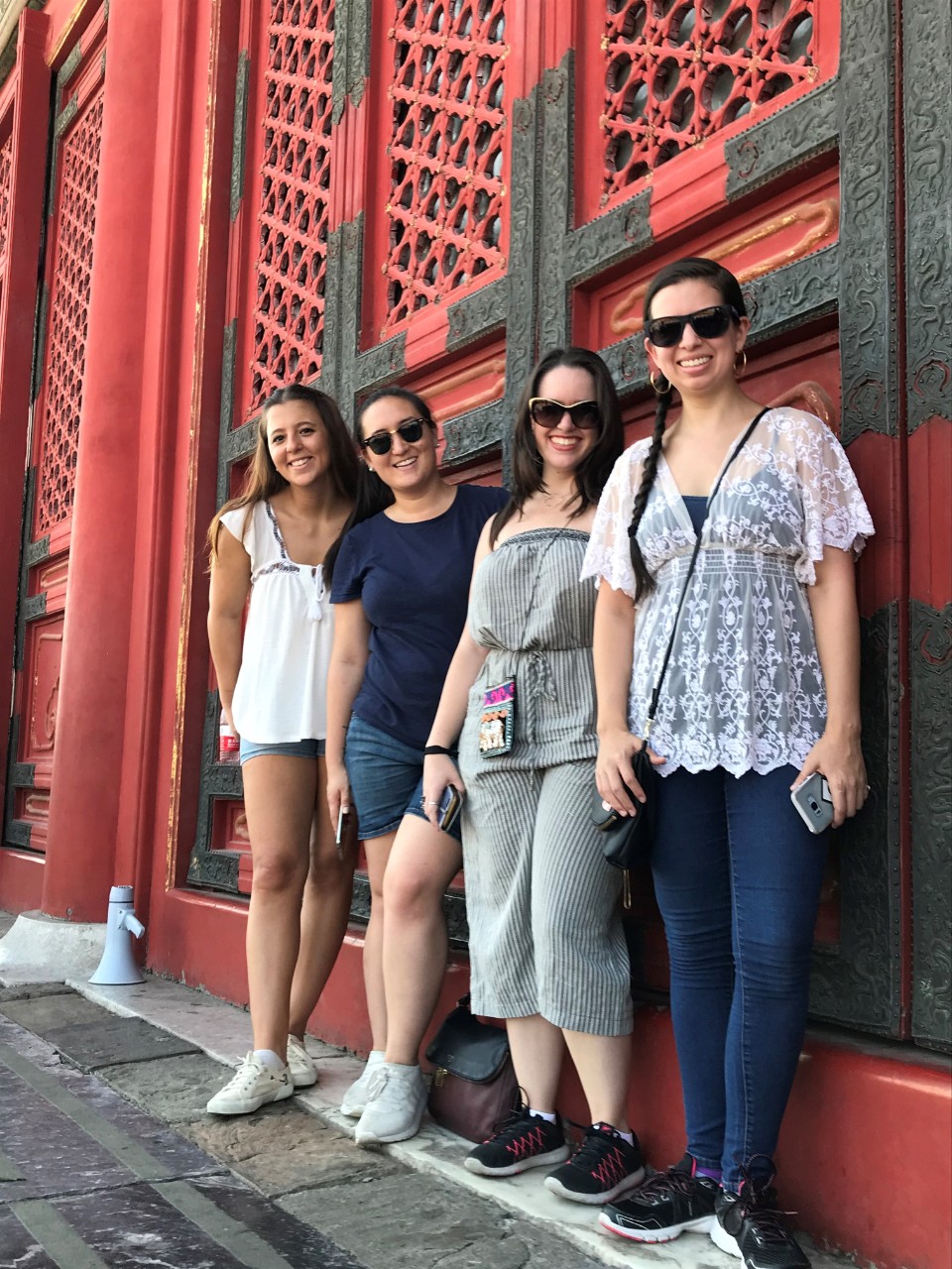 4 students posing in front of a redish building