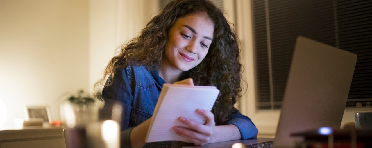 An online degree student takes notes while engaging in online learning.