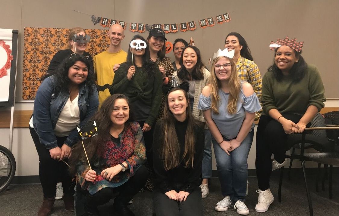 Publishing Students Association (PSA) members pose in masks and costumes beneath a banner that reads "Happy Halloween"