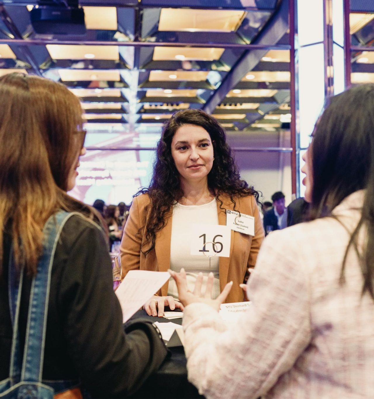 Three female NYU SPS students meet and greet each other at a career networkign event.
