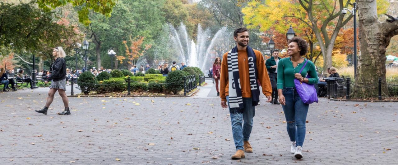 Two NYU SPS students walk together in Central Park in the fall.